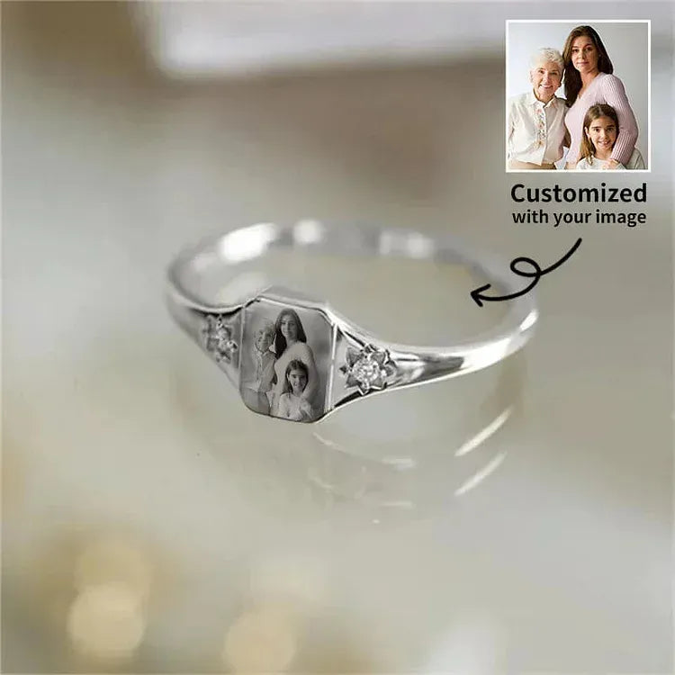 Silver ring with family portrait engraving on a light background