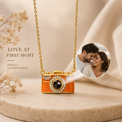 Camera-shaped projection pendant necklace on a beige surface with a couple in a circular inset.