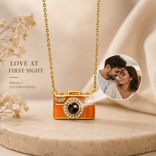 Camera-shaped projection pendant necklace on a beige surface with a couple in a circular inset.