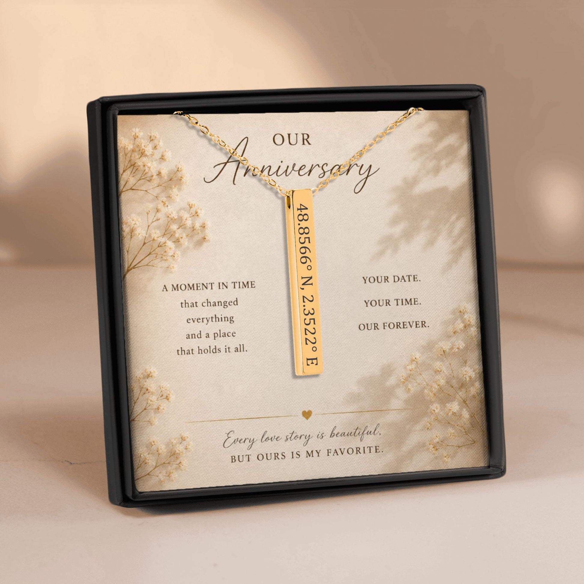 Gold necklace with a bar pendant on a decorative card in a black box