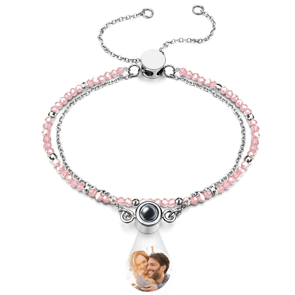 Bracelet with pink beads and a teardrop-shaped charm featuring a photo of a couple.