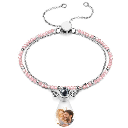 Bracelet with pink beads and a teardrop-shaped charm featuring a photo of a couple.