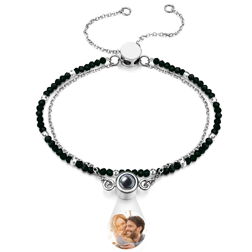 Bracelet with black beads and a teardrop-shaped charm featuring a photo of a couple.