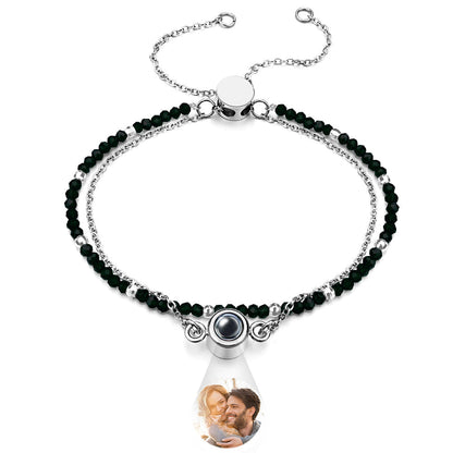 Bracelet with black beads and a teardrop-shaped charm featuring a photo of a couple.