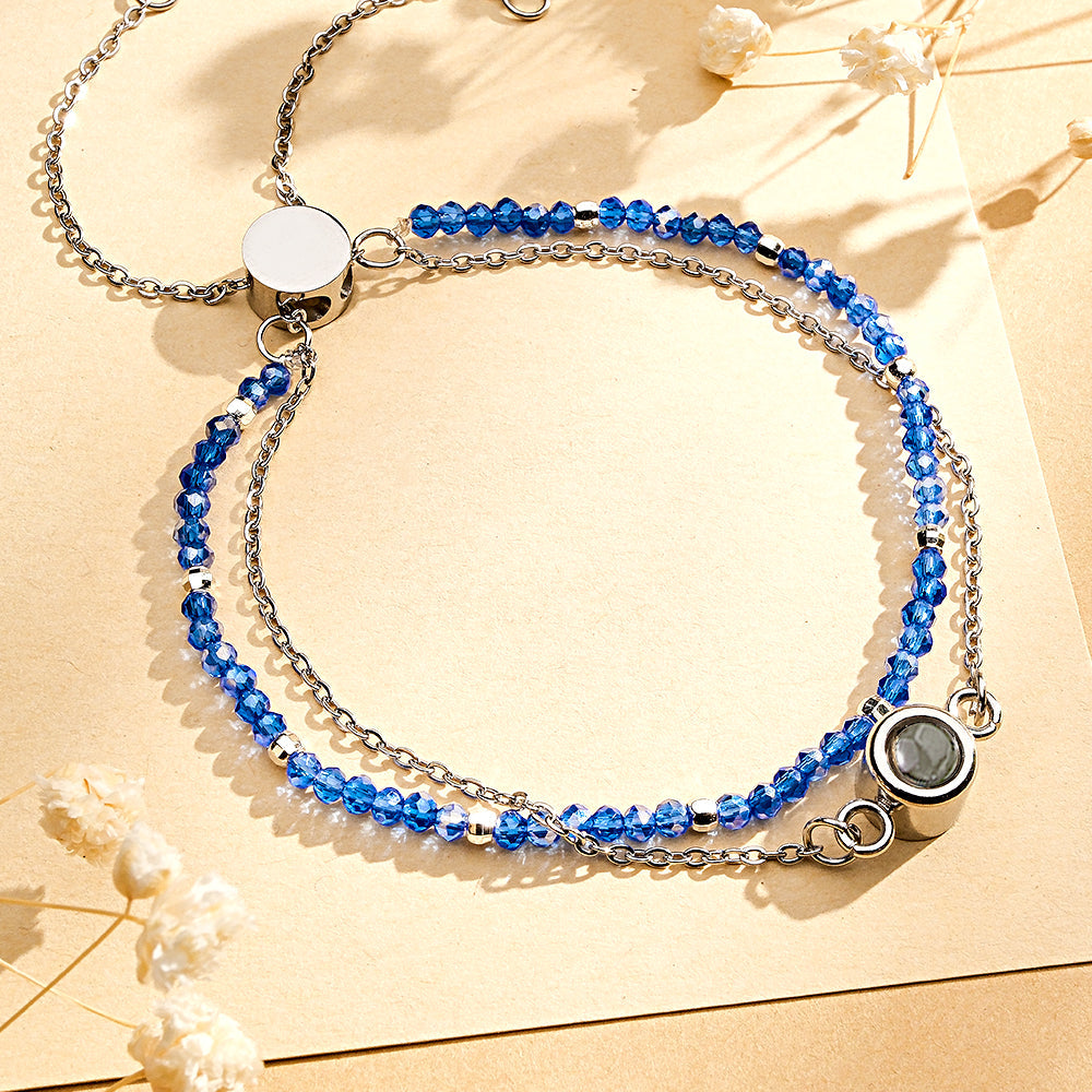 Double-layered bracelet with blue beads and silver chain on a beige background