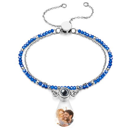 Bracelet with blue beads and a teardrop-shaped charm featuring a photo of a couple.