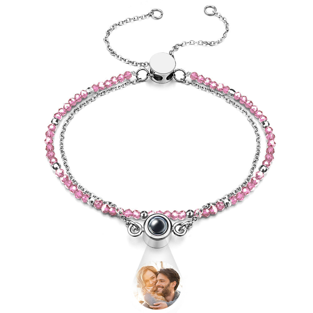 Bracelet with pink beads and a teardrop-shaped charm featuring a photo of a couple.