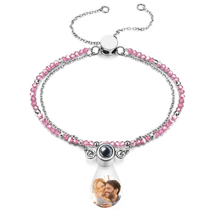 Bracelet with pink beads and a teardrop-shaped charm featuring a photo of a couple.