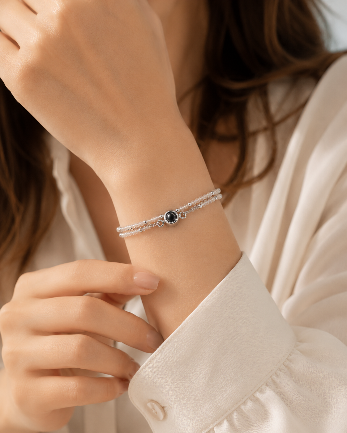 Close-up of a person wearing a silver bracelet with a blue stone on a light background