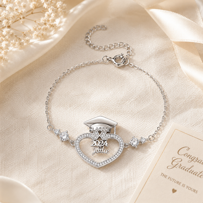 Silver bracelet with graduation cap design on a beige fabric background