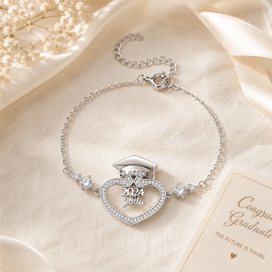Silver bracelet with graduation cap design on a beige fabric background