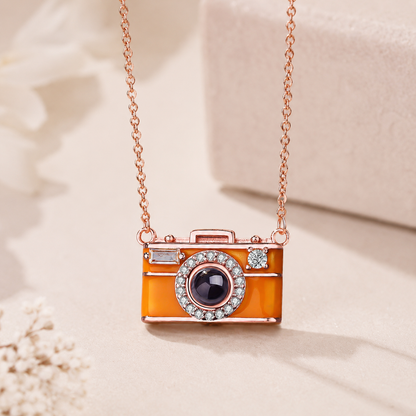 Camera-shaped projection pendant necklace on a soft beige background