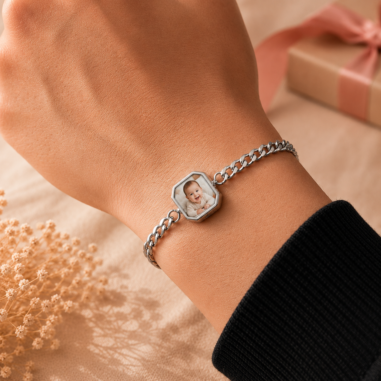 Bracelet with a hexagonal charm featuring an engraved image of a baby on a wrist, with a soft blurred background.