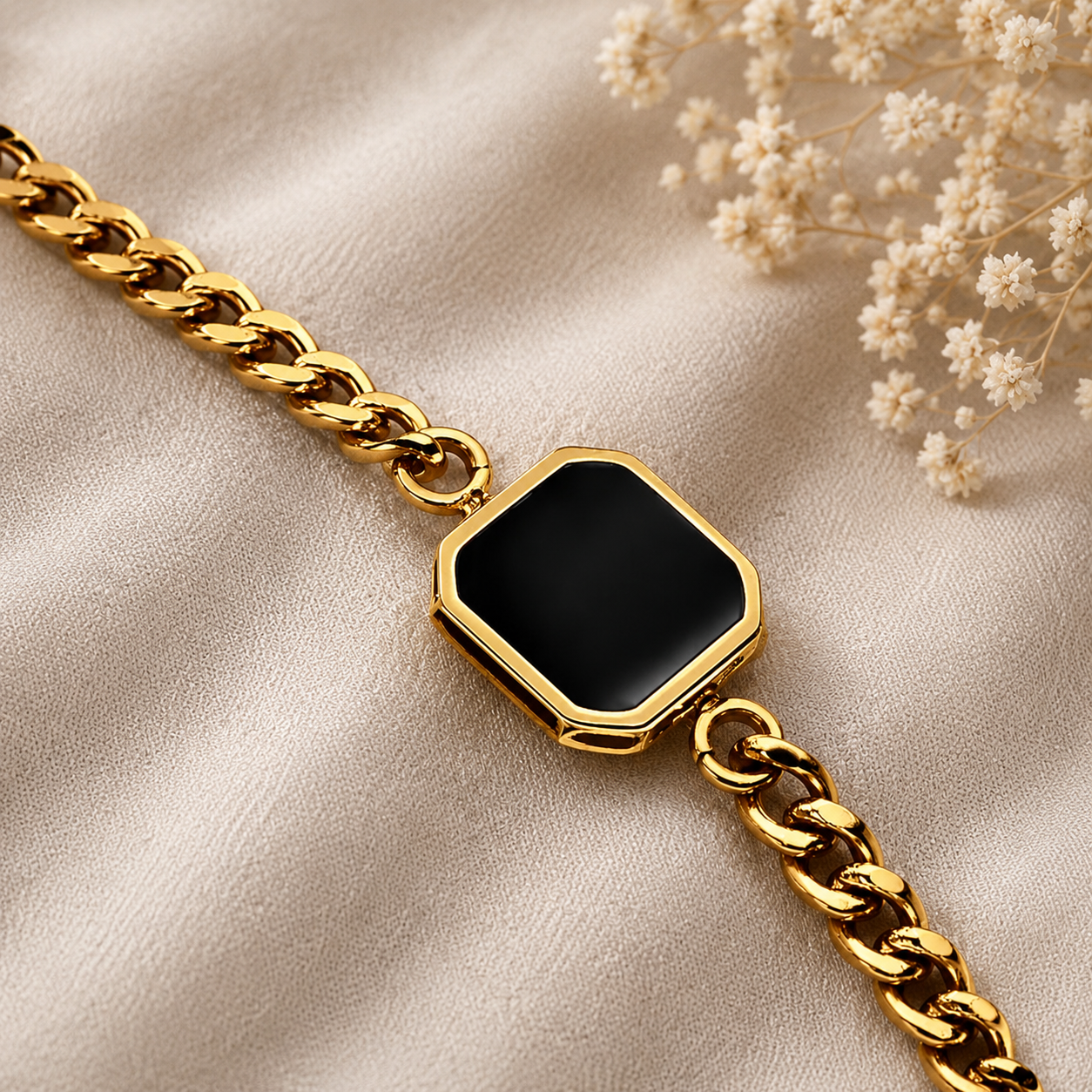 Gold bracelet with a black gemstone on a beige fabric background