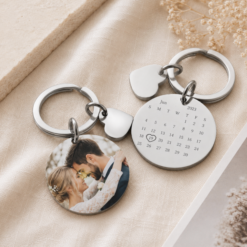 Keychain with photo charm and calendar charm on a beige fabric background