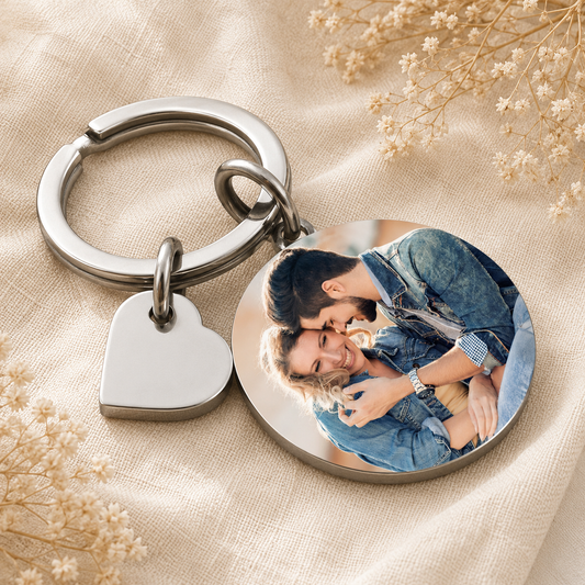 Keychain with heart tag and circular photo charm featuring a couple on a beige fabric background.