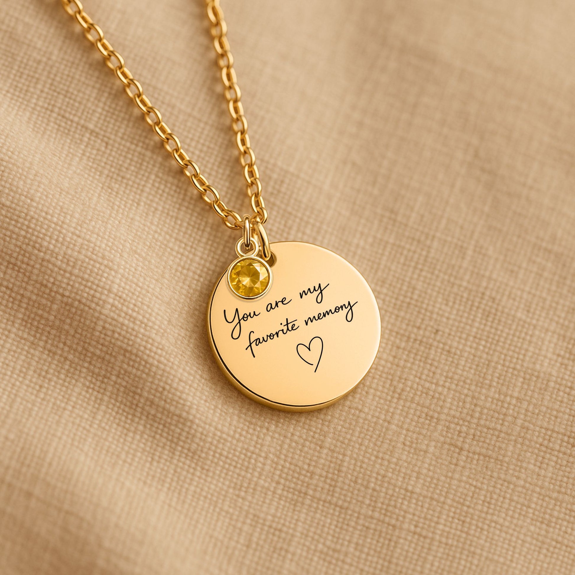 Personalized birthstone necklace with You Are My Favorite Memory engraving photographed on neutral fabric background